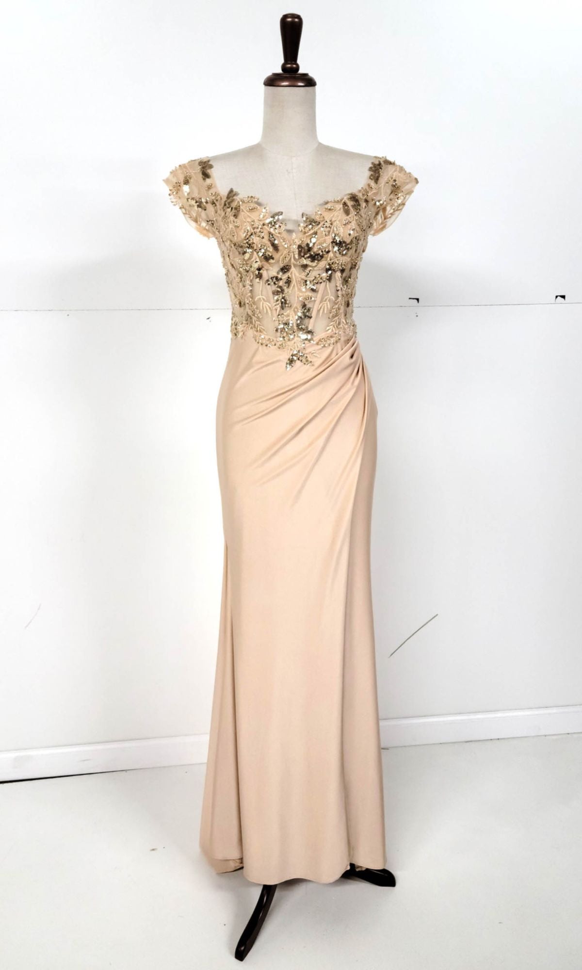 The Sequin-Bodice Long Prom Dress (Chicas YG5027) is a beige, floor-length gown with off-the-shoulder short sleeves and a sequin corset bodice decorated with gold floral embellishments, shown on a dress form.
